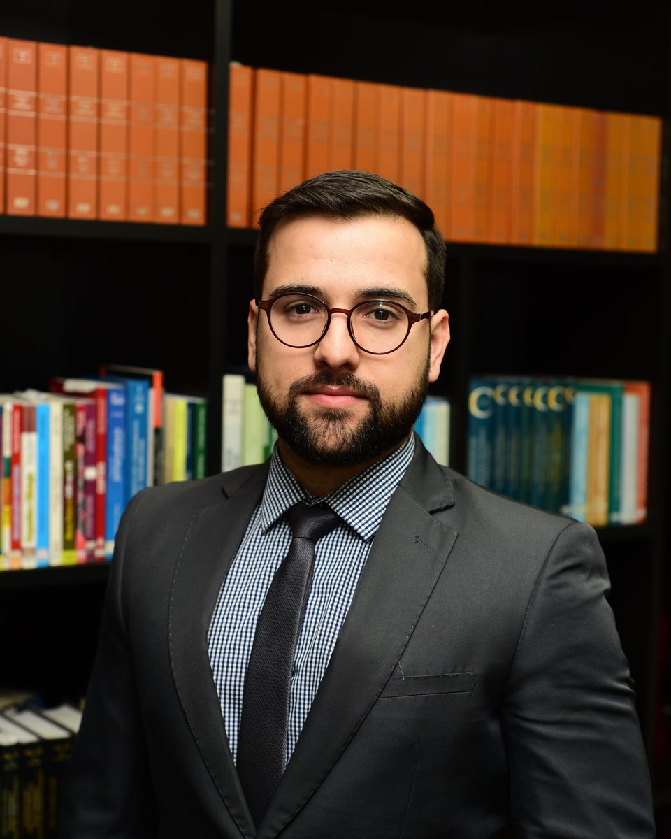 Retrato do advogado Eduardo Martins Sessim diante de uma estante de livros jurídicos